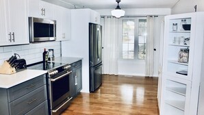 A modern kitchen with white cabinetry, stainless steel appliances, and a wooden floor. - Beautiful lakefront retreat, 4 bedroom, sleeps 8 (Huntsville)