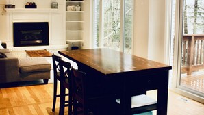 A modern living room with a wooden dining table, a fireplace, a sofa, and a TV. - Beautiful lakefront retreat, 4 bedroom, sleeps 8 (Huntsville)