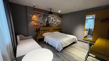 Habitación de hotel con cama, sofá, una mesita y una pared con diseños circulares, además de una ventana con cortinas.