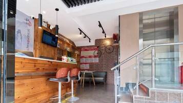 Un interior moderno con una barra de madera, taburetes, un televisor y una escalera.
