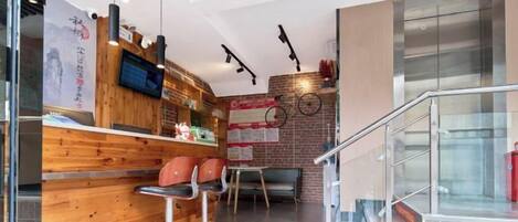 A modern interior with a wooden counter, bar stools, a television, and a staircase.