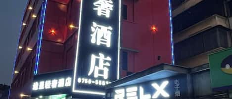 A hotel with a prominent vertical sign displaying its name in large characters.