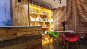 Ein Empfangsbereich mit einem Holztresen, einem Bücherregal und zwei Stühlen.