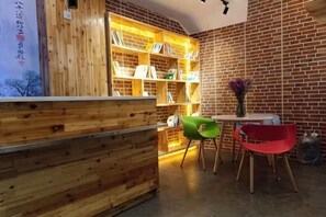 A reception area with a wooden reception desk, a bookshelf, and two chairs. - Tuke Boutique Hotel (Taishan)
