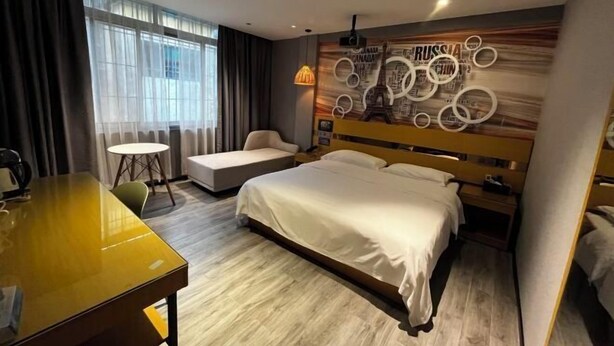Ein Hotelzimmer mit einem Bett, einer Sitzecke, einem Tisch und einer Wand mit kreisförmigen Mustern und Text.