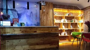 Ein Empfangsschalter mit Holzoptik, eine Backsteinwand und eine Bücherregal mit Büchern.