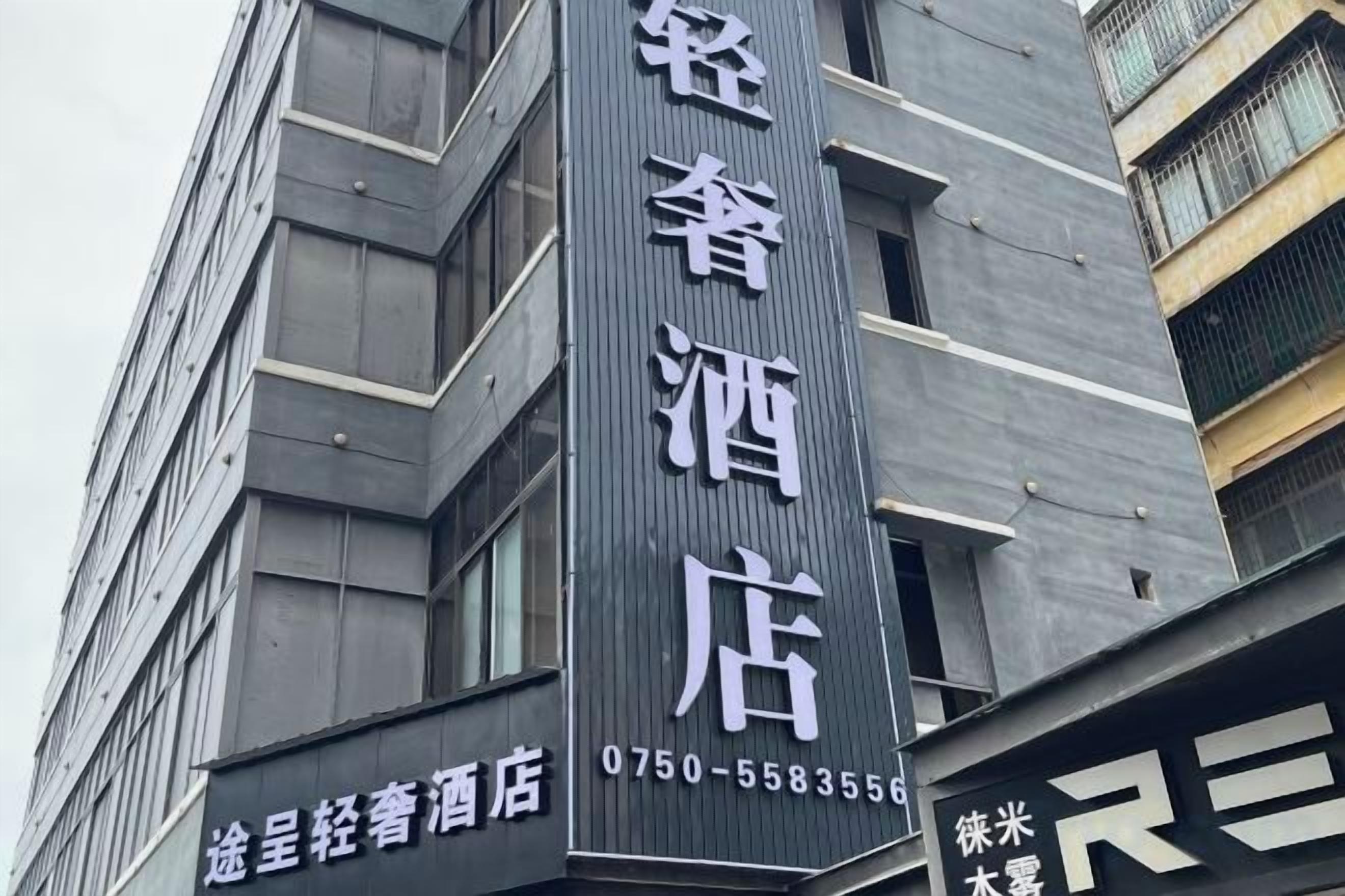 A building with a vertical sign indicating a hotel. The sign includes a phone number.