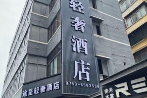 A building with a vertical sign indicating a hotel. The sign includes a phone number. - Tuke Boutique Hotel (Taishan)