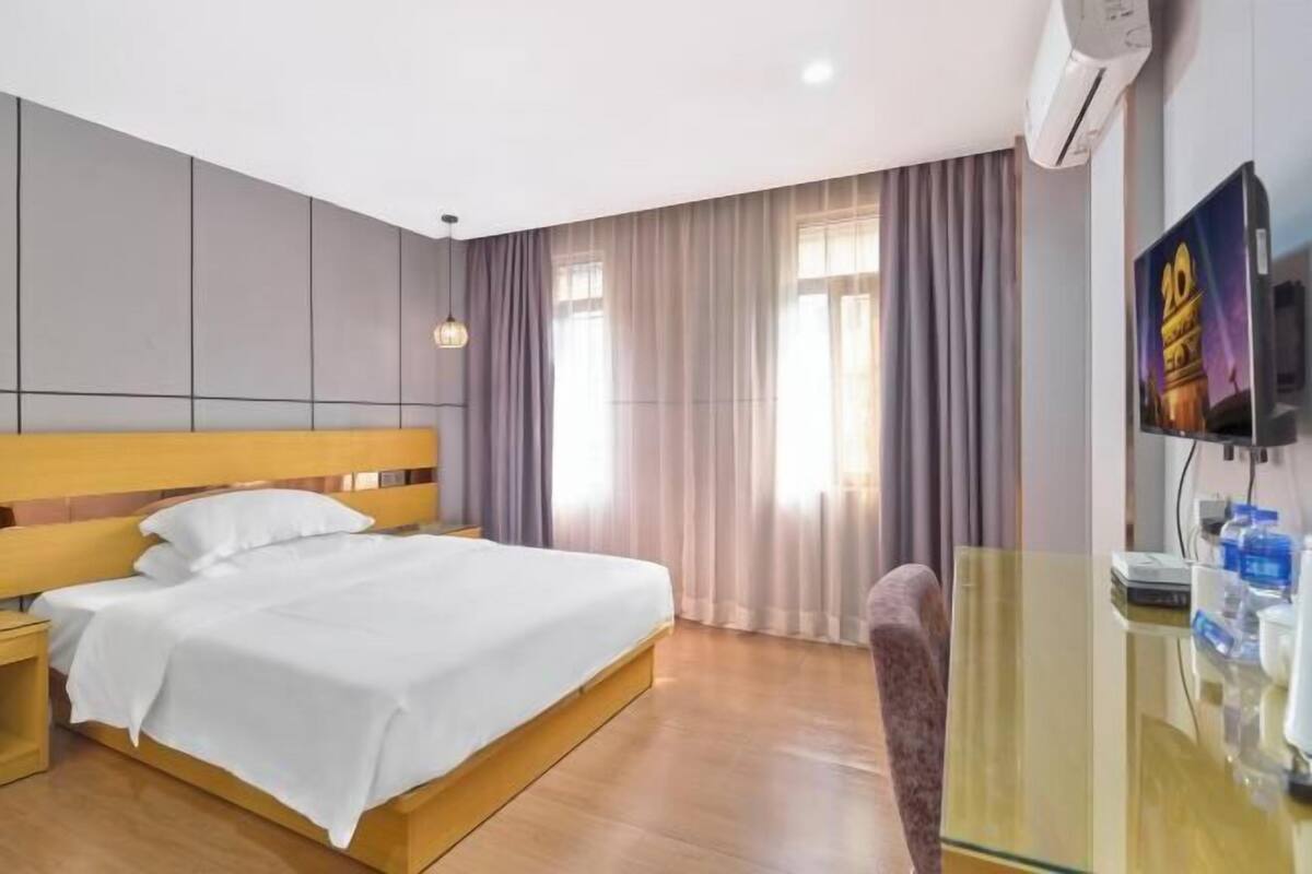 A hotel room with a bed, a TV, a desk, and a chair.