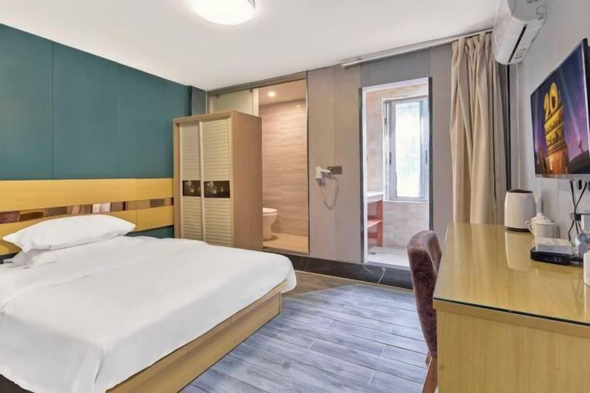 A hotel room with a bed, a desk, a TV, and a bathroom.