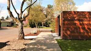 Une allée menant à une résidence, avec un trottoir, un arbre et une maison dotée d’un garage.