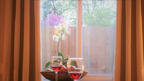 Une table à manger dressée pour deux personnes, avec un vase de fleurs et deux verres à vin.