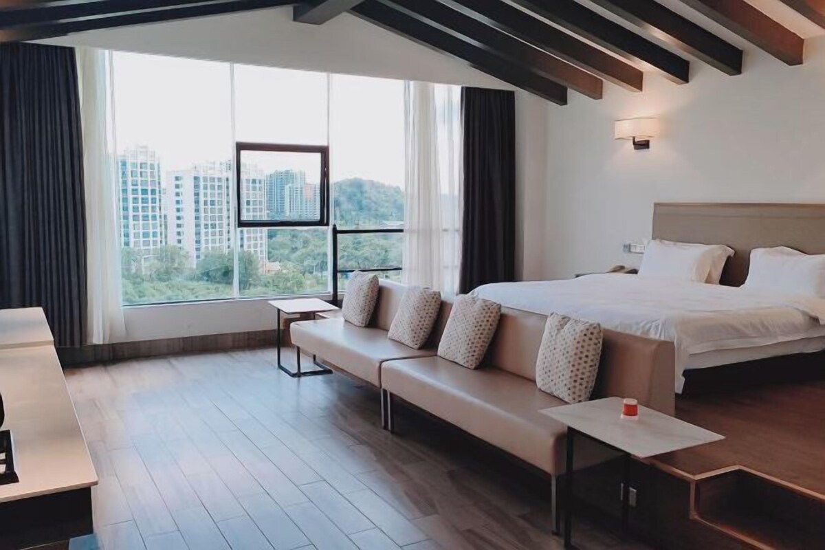 A modern hotel room with a large bed, a sofa, a small table, and a TV.