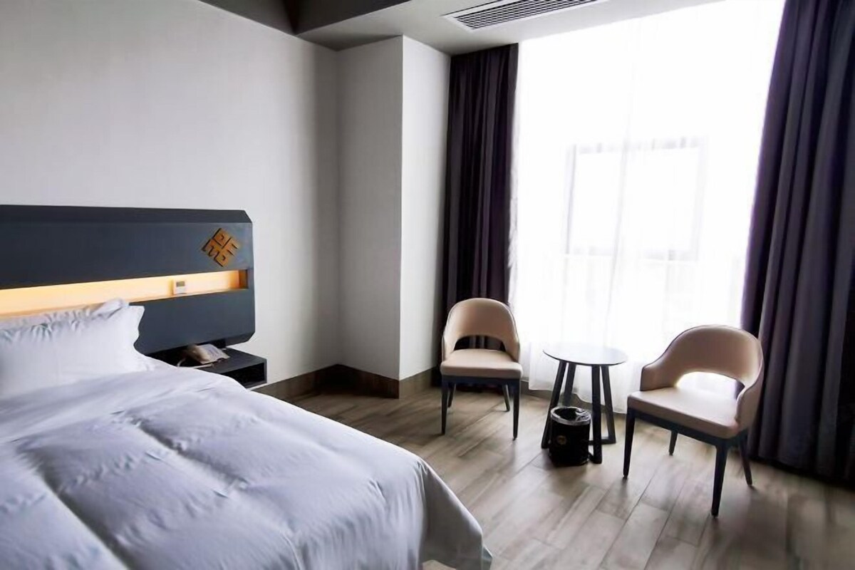 A hotel room with a bed, a desk, two chairs, and a small table.
