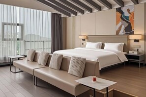 A hotel room with a large bed, a sofa, a bedside table, a nightstand, and a window with curtains. - Bengenei Hotel (Qiongzhong)