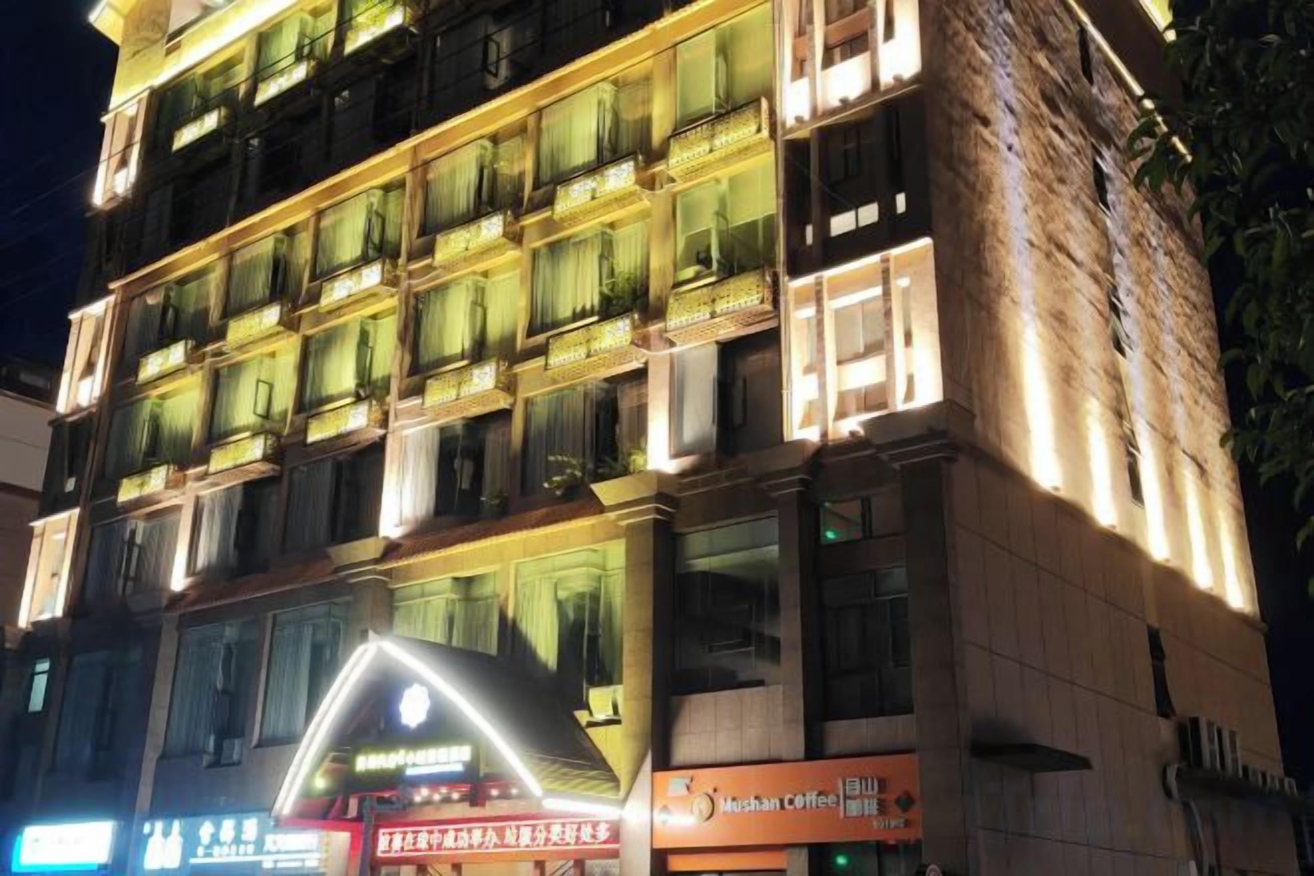 Un hotel de varios pisos con balcones iluminados y señalización para una cafetería.