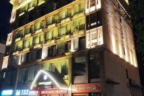 A multi-story hotel with illuminated balconies and signage for a coffee shop. - Bengenei Hotel (Qiongzhong)