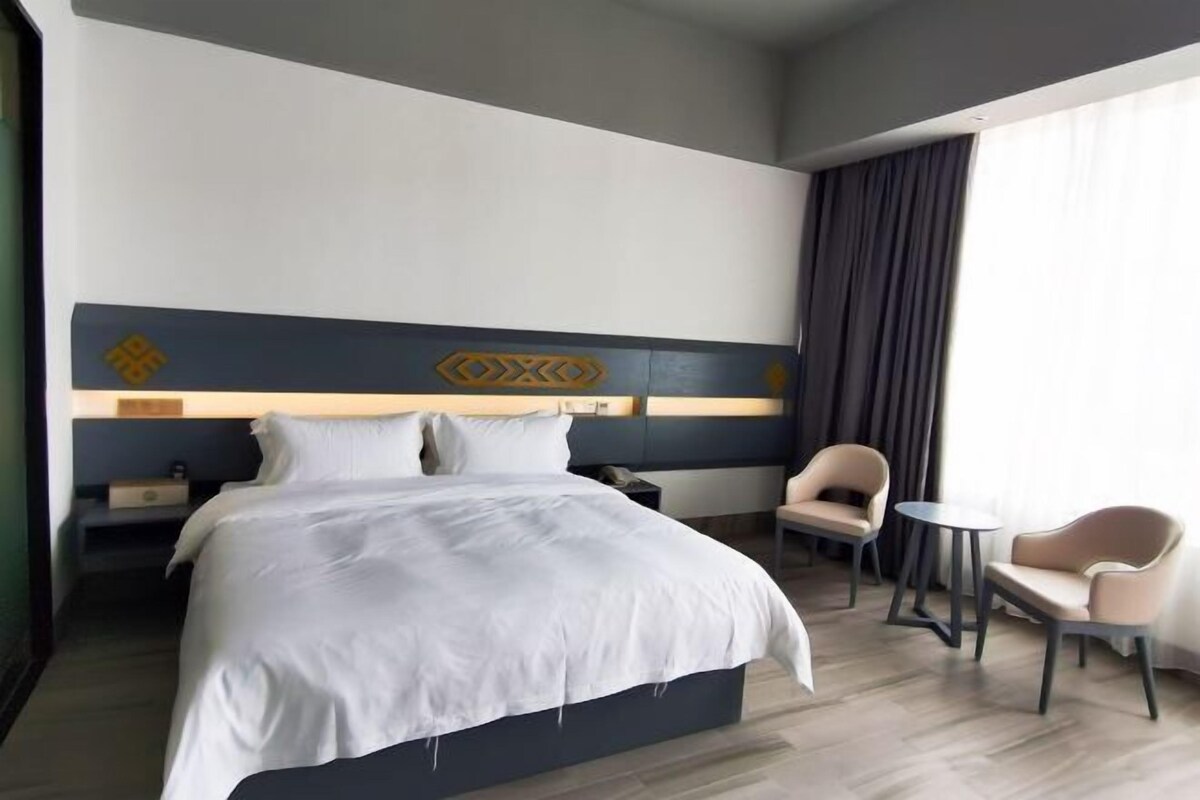 A hotel room with a large bed, two bedside tables, a desk, and two chairs.