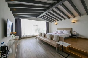 A modern hotel room with a large bed, a sofa, a small table, and a TV. - Bengenei Hotel (Qiongzhong)