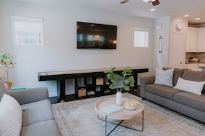 A living room with a sofa, a coffee table, a TV, and a bookshelf.