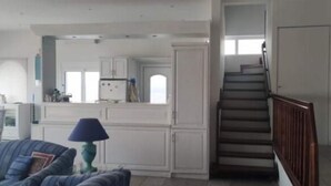 Tilava olohuone, jossa on keittiö, portaikko ja ruokailutila.