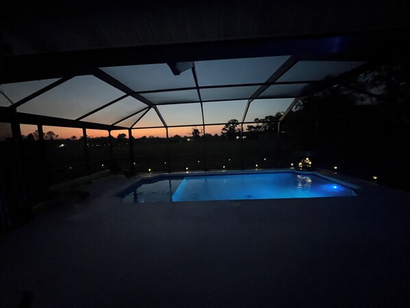 Une piscine intérieure dotée d’un toit en verre, entourée d’un espace sombre et clos, éclairé de façon minimale.