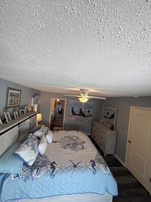 Une chambre à coucher avec un lit, une commode et un ventilateur de plafond.