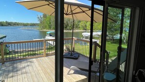 Une terrasse en bois avec une rambarde en verre, des meubles d’extérieur et un grand parasol.