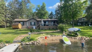 Une propriété au bord du lac, dotée d’un quai, d’un petit étang et d’une maison avec une terrasse.