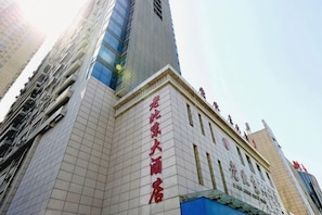 A tall building with a prominent entrance and signage indicating a hotel.