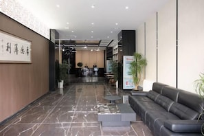 Un vestíbulo de hotel con mostrador de recepción, zona de estar y mostrador de información.