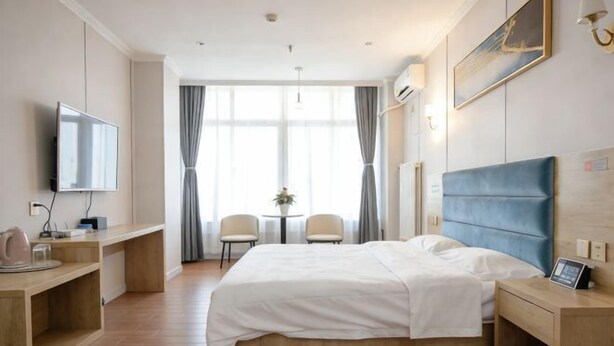 Une chambre d’hôtel avec un lit, des tables de chevet, une télévision, un bureau et une fenêtre avec des rideaux.