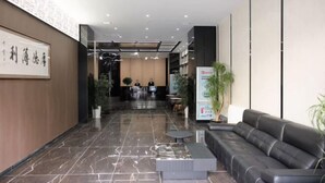 Un hall d’hôtel comprenant un comptoir d’accueil, un espace salon et un mur orné d’un tableau encadré.