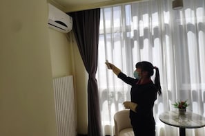 Una habitación con ventana, una silla, una mesa y un equipo de aire acondicionado.