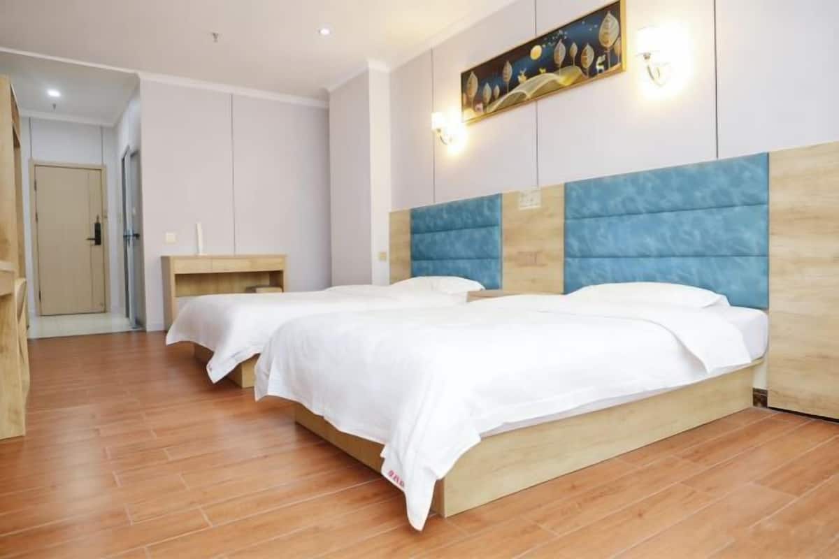 Une chambre d’hôtel avec deux lits, une tête de lit en bois, une table de chevet et un tableau au mur.