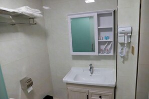 A bathroom with a sink, a mirror, a towel rack, a soap dispenser, and a hairdryer. - Shangluo Old Beijing Hotel (Shangluo)