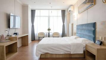 A hotel room with a bed, bedside tables, a desk, a chair, a TV, and a window with curtains.