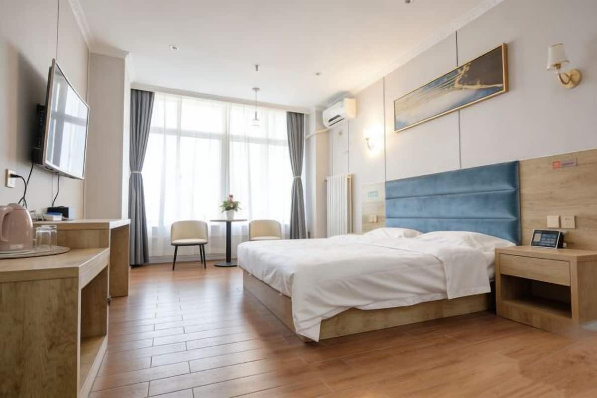 Une chambre d’hôtel avec un lit, une table de chevet, une télévision et une fenêtre avec des rideaux.