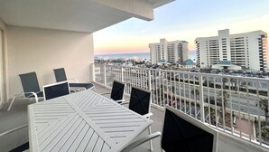 A balcony with a table and chairs, overlooking a cityscape with buildings and a road.