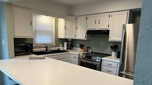 Een moderne keuken met witte kasten, roestvrijstalen apparatuur en een groot eiland.
