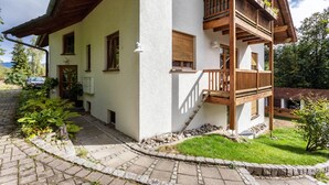 Un bâtiment à deux étages doté d’un balcon, d’un chemin pavé de pierres et d’une zone herbeuse.