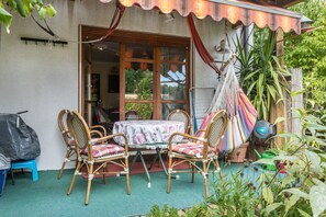 Un patio con sillas de mimbre, una mesa y una hamaca.