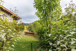 Un jardín con una valla de madera, una estructura de techo de paja y abundante vegetación.