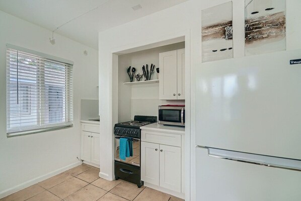 A compact kitchen with white cabinets, a gas stove, a microwave, and a refrigerator. - ππ Breathtaking 1 Bedroom ~ Prime Singer Island ππ (West Palm Beach)
