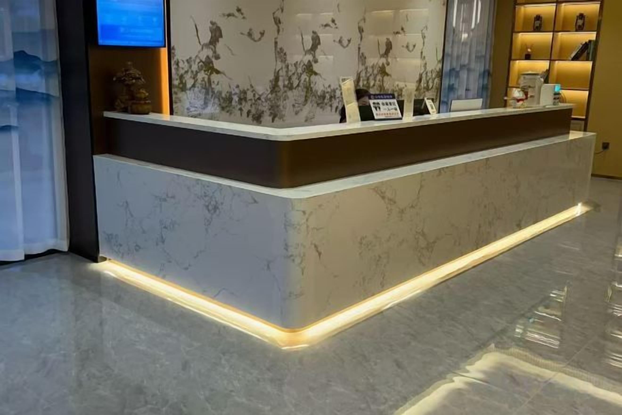 Una recepción con detalles de mármol y una base iluminada.