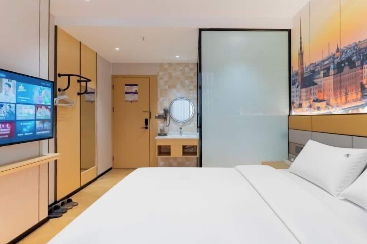 Ein Hotelzimmer mit einem Bett, einem Fernseher, einem Spiegel und einem Stadtbild.