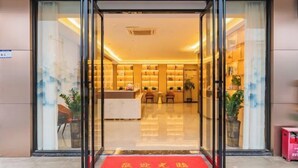 A hotel entrance with a reception desk, chairs, and a red carpet with 'Welcome' written on it. - Huizhou galston hotel (Huizhou)