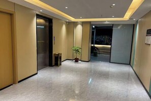 Een hotelgang met een gepoetste vloer, een lift en een kamerplant.