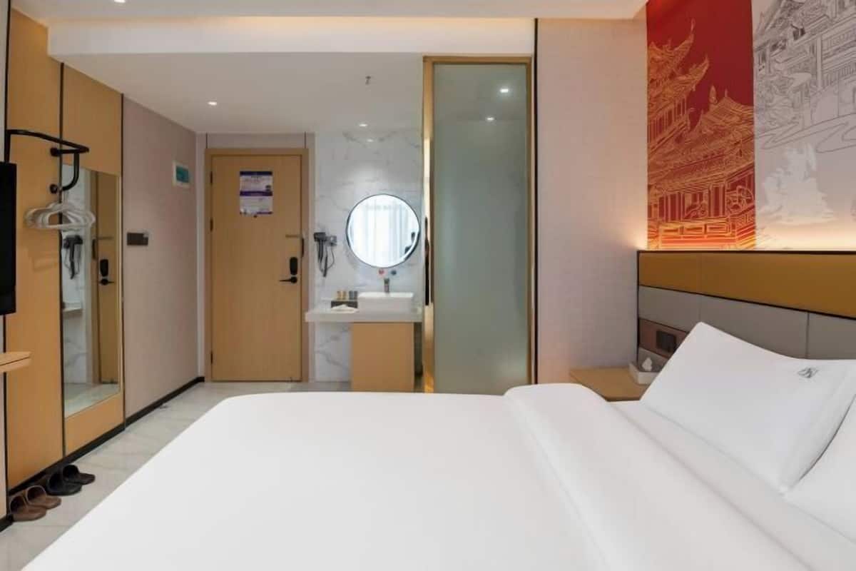 Ein Hotelzimmer mit Bett, Spiegel, Waschbecken und Kleiderschrank.