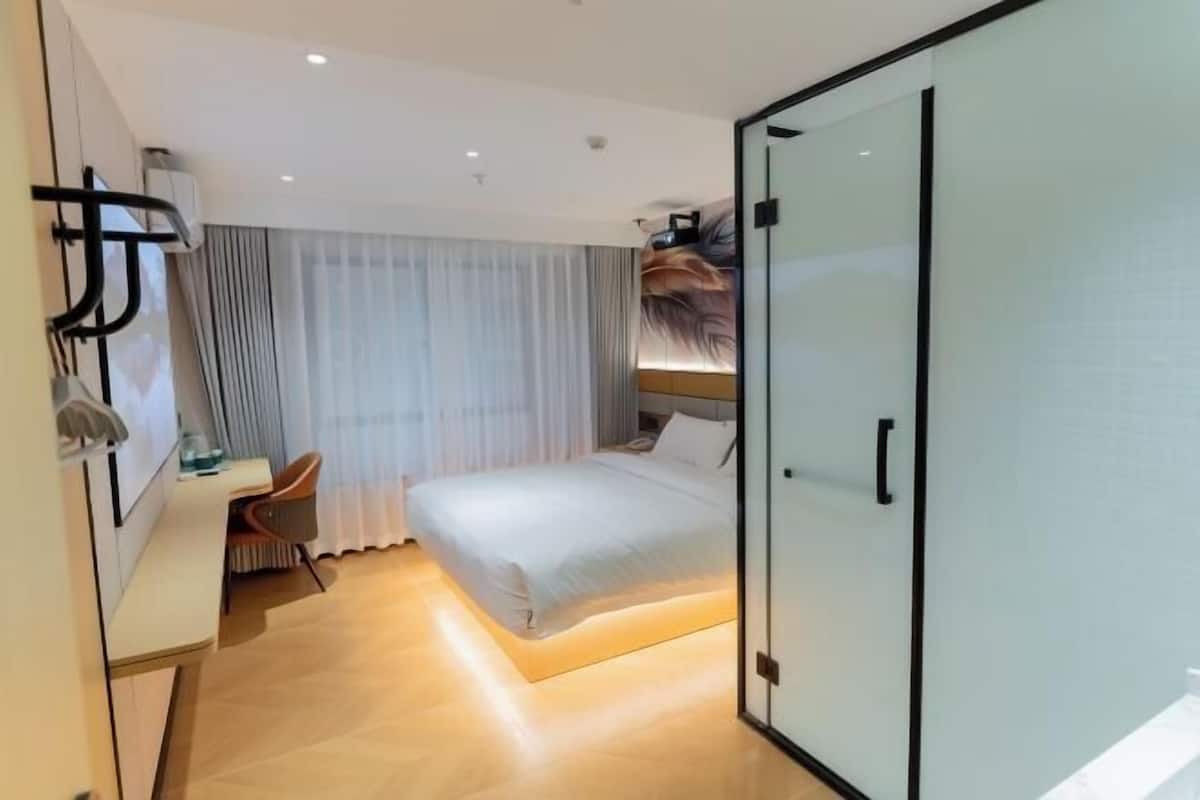 Ein modernes Hotelzimmer mit Bett, Schreibtisch, Stuhl und Kleiderschrank.